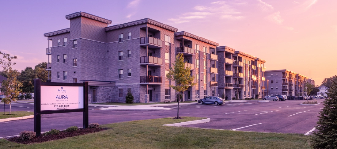 Exterior view of a four-storey apartment property at twilight.